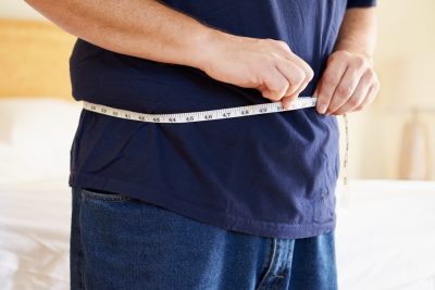 overweight man measuring belly