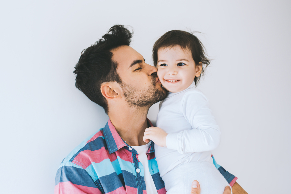 dad kissing his young daughter